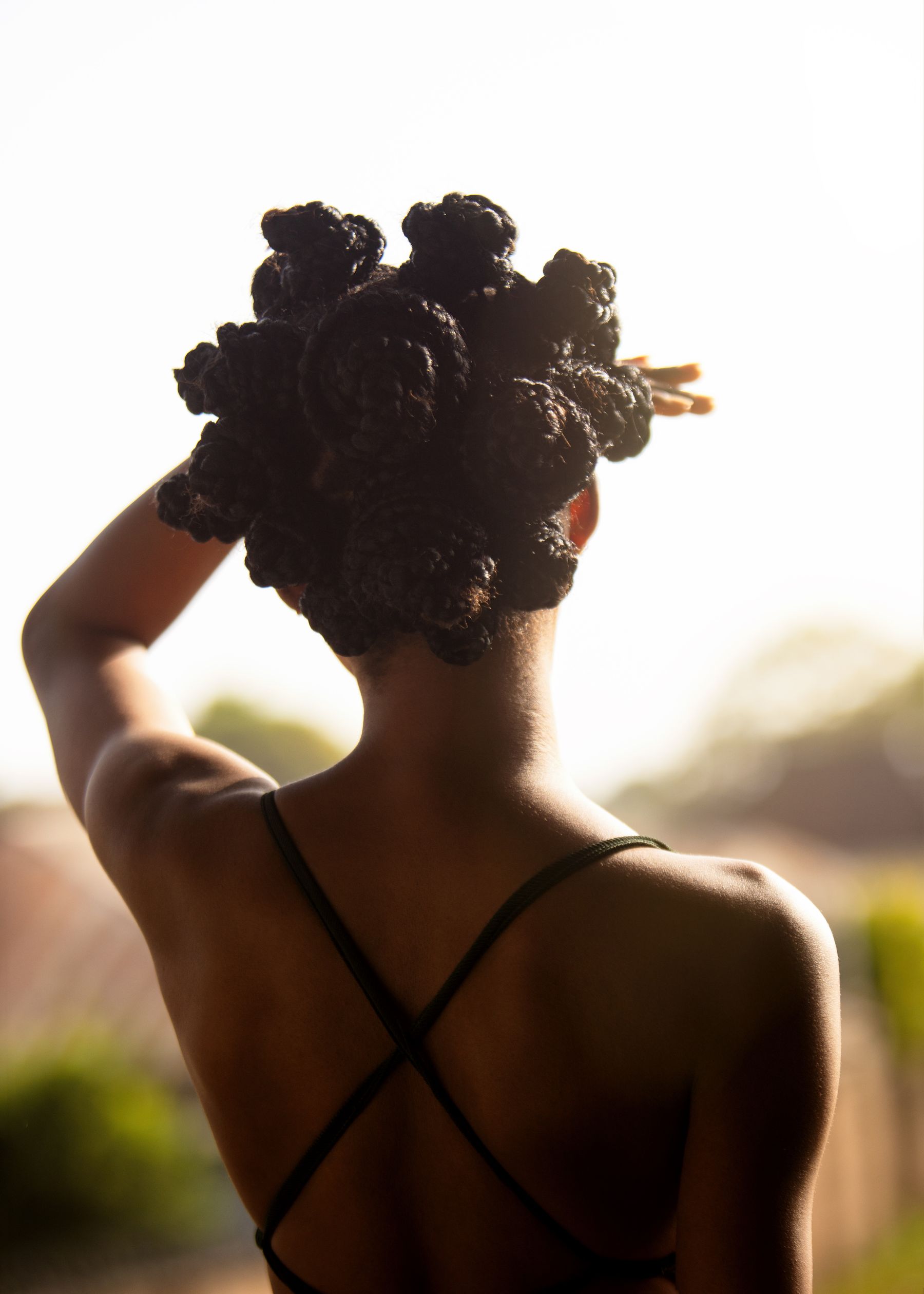 Back view of a woman with intricately braided hair in sunlight